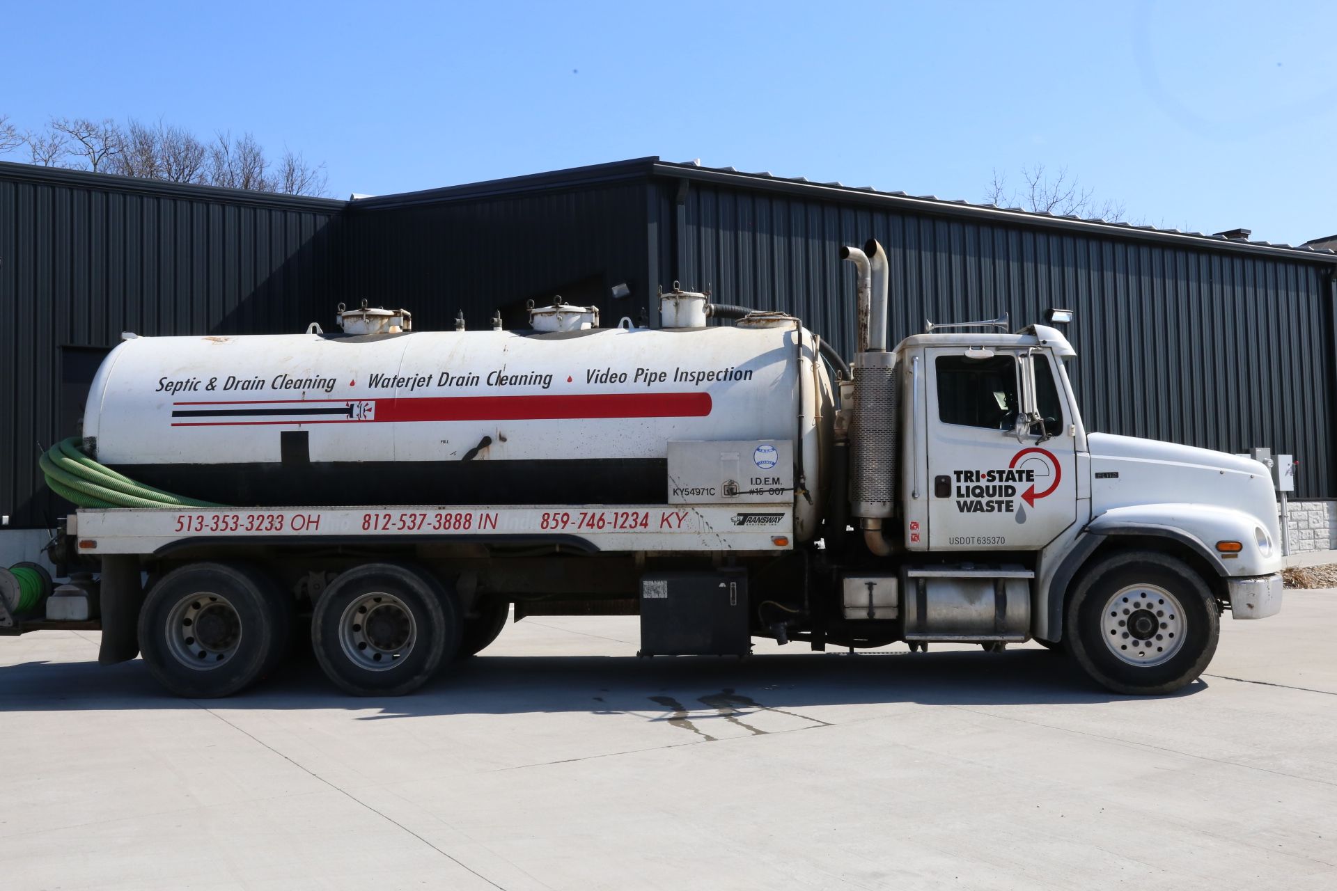 a white vacuum truck is parked in front of a building .