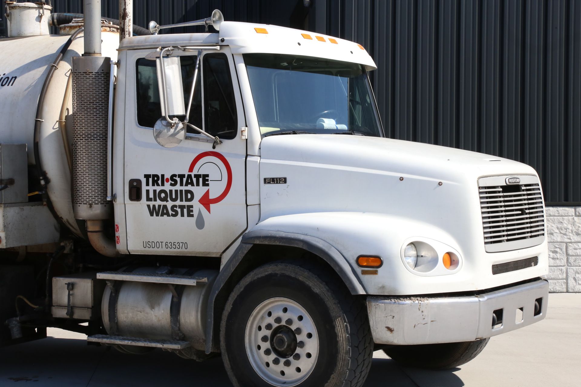 a tri-state liquid waste truck is parked in front of a building