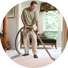 A man cleaning a carpet using a vacuum cleaner