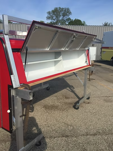 Red and white storage compartment on wheeled stand, lid open showing shelves.