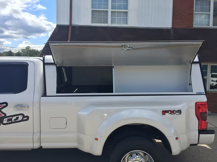White pickup truck with an open, aluminum bed cover.