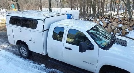 White pickup truck with utility bed in a snowy area.