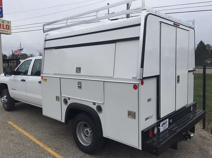 White work truck with a utility bed, parked outside.