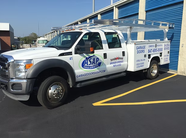 White ASAP truck parked next to blue storage units. Truck has ladder rack and company logo.