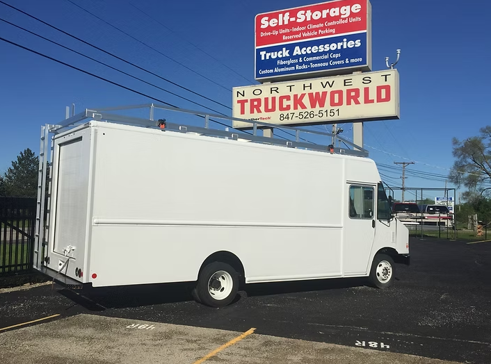 White delivery truck with ladder rack at Northwest Truckworld store.