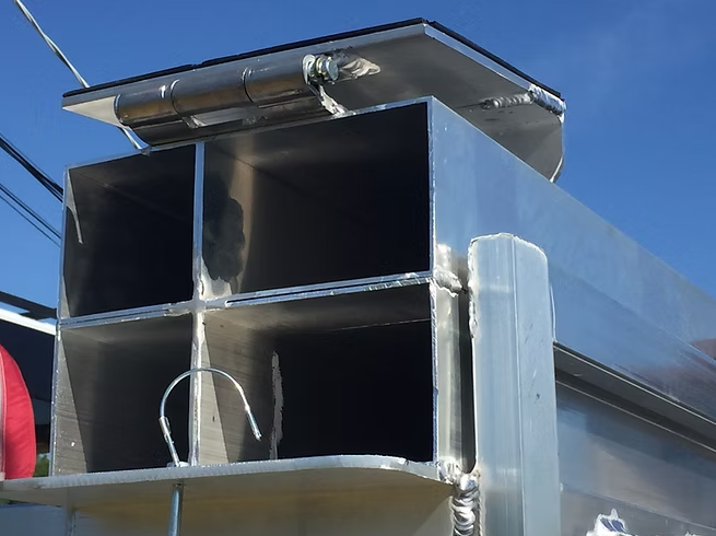 Shiny metal container with four square openings and a hinged lid, against a blue sky.