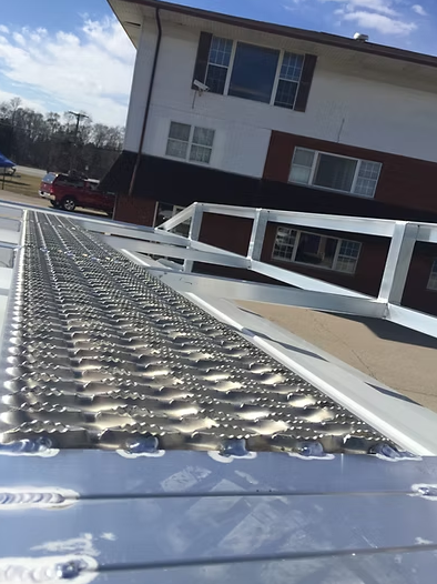 Metal ramp on a white structure, angled upward. Building with white and brick exterior in background.