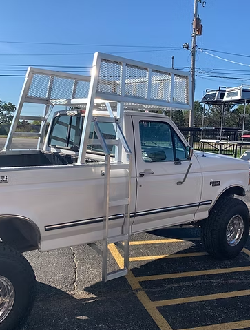 White pickup truck with a large, metal cargo rack and ladder, parked outdoors.