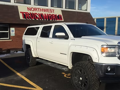 White truck with a camper shell parked in front of Northwest Truckworld.
