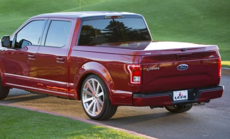 Red Ford F-150 pickup truck with a Leer bed cover on a golf course.