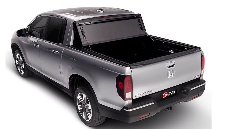 Silver Honda Ridgeline pickup truck with black bed cover open.
