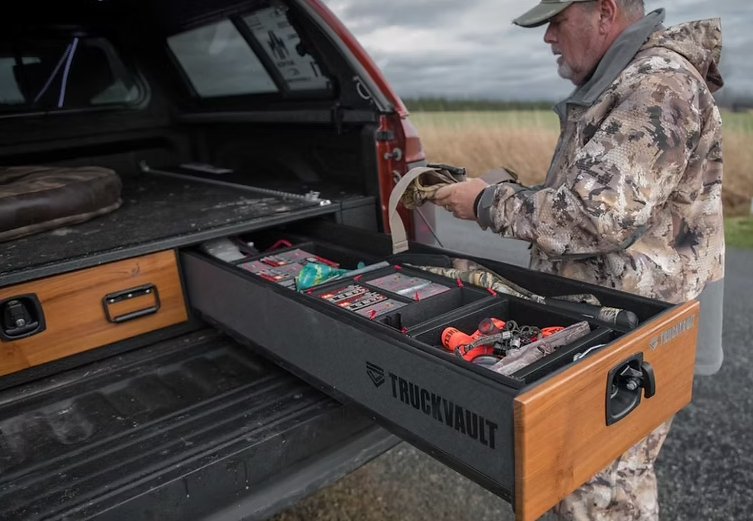 Man in camo opens truck drawer, retrieves items. Drawer labeled 