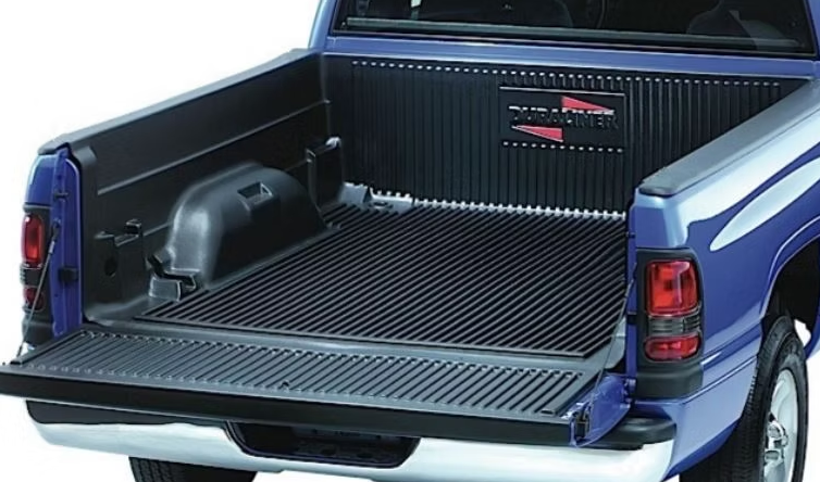 Blue pickup truck bed with a black rubber bed mat. The tailgate is down.