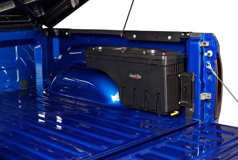 Black tool box mounted on the side of a blue pickup truck bed.