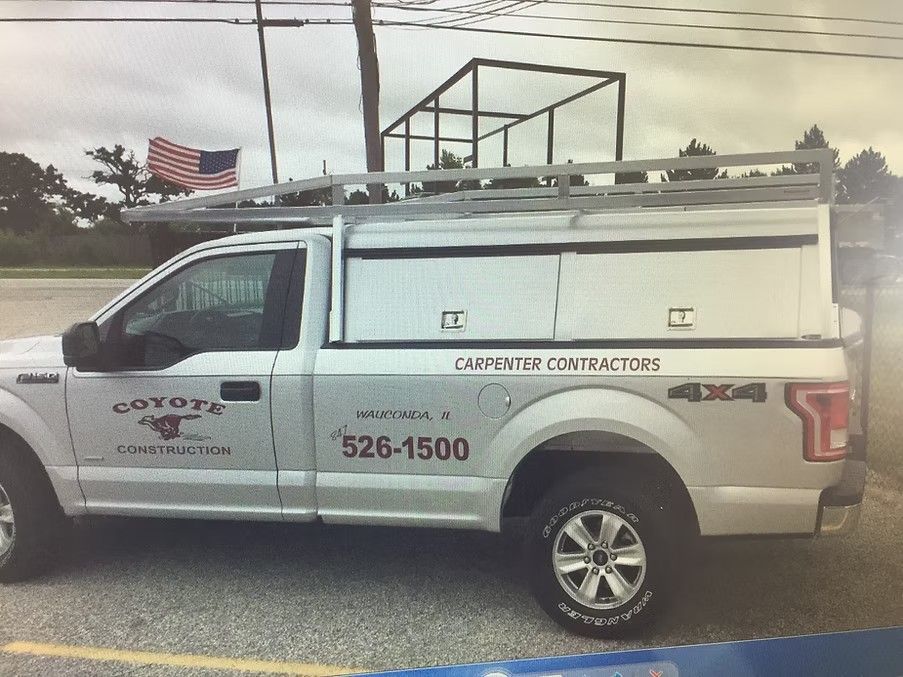 Silver pickup truck with storage compartments and ladder rack, marked with 