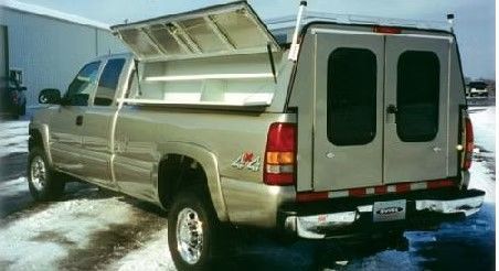 Gold pickup truck with a custom utility cap, doors open to reveal shelves.