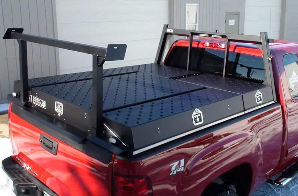 Red pickup truck with a black utility bed and rack, outdoors.