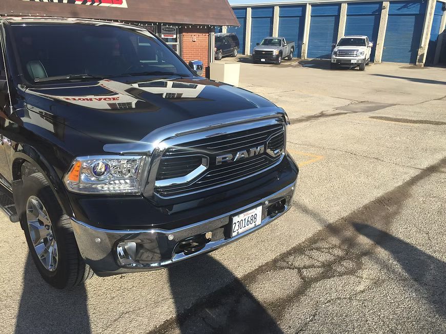 Black Ram pickup truck parked in front of storage units on a sunny day.