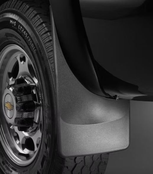 Black Chevrolet pickup truck mud flap next to a tire.