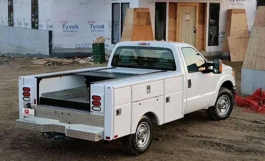 White work truck with toolboxes parked at a construction site.
