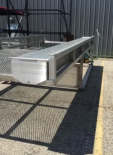 Aluminum industrial platform with perforated metal sides and a long, flat surface. Outdoors, casting a shadow.