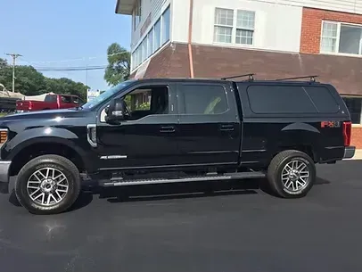 Black Ford pickup truck with a cap parked in front of a building.