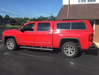 Red pickup truck with a cap parked outside on a sunny day.