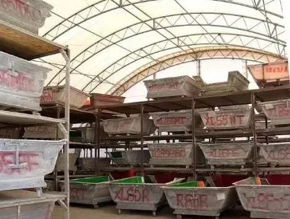 Shelves filled with rectangular, labeled containers inside a white-roofed structure.