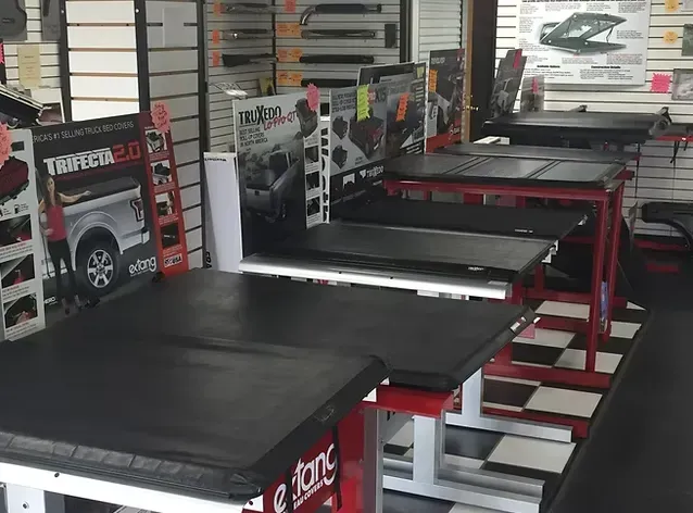 Truck bed covers displayed on red stands in a store.
