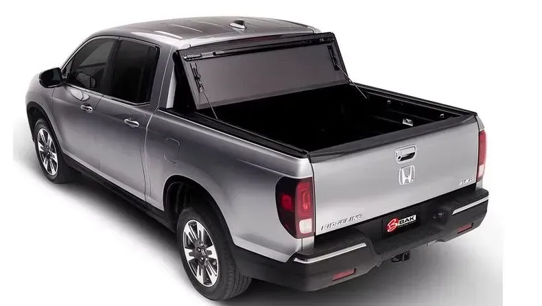 Silver Honda Ridgeline pickup truck with a black tonneau cover, on a white background.
