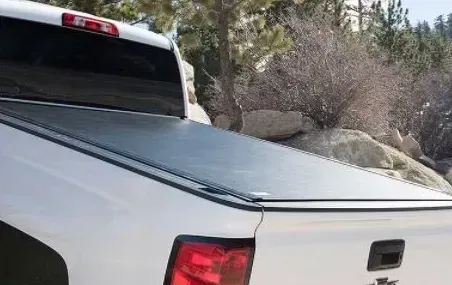 White pickup truck with a black tonneau cover in an outdoor setting.