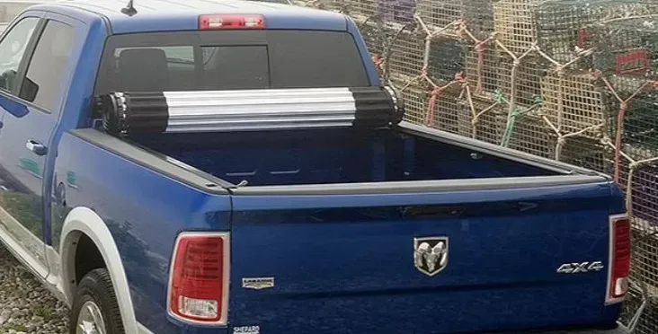Blue pickup truck with open bed and roll-up cover, next to lobster traps.