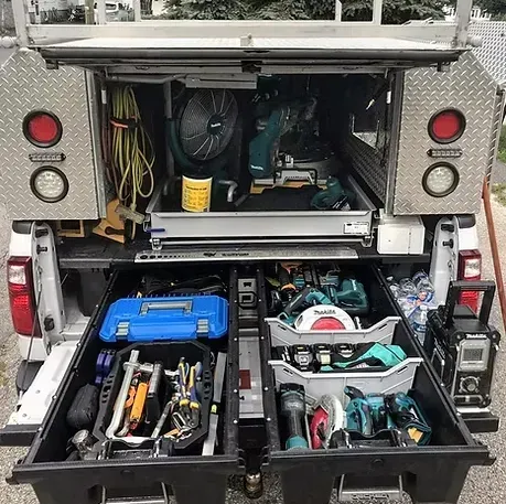Truck bed with open drawers holding tools and equipment. White truck, gray drawers, and tools.