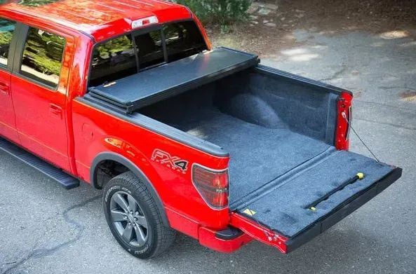 Red pickup truck with bed cover open, showing the inside with a bed liner.