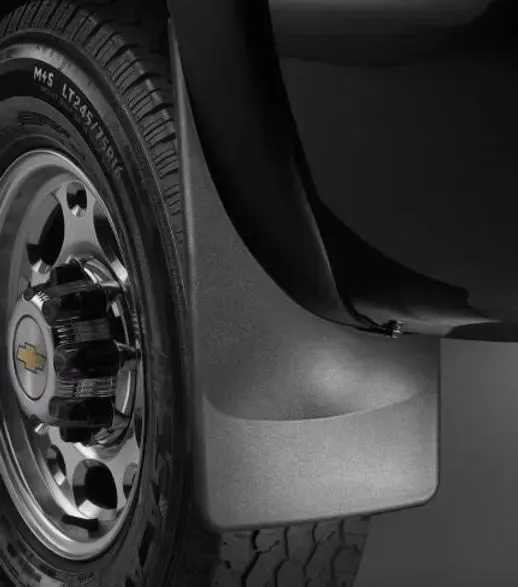 Black truck mud flap next to a chrome wheel and tire.