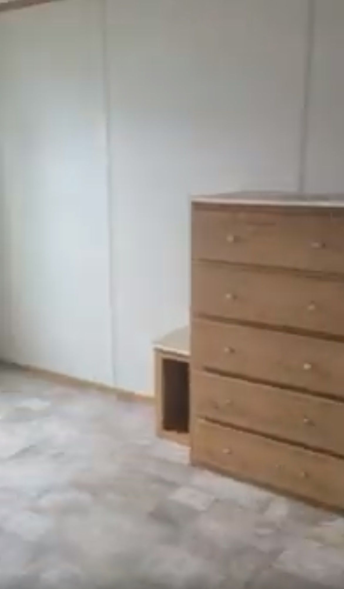 Wooden dresser and small cabinet in a room with light flooring and white walls.
