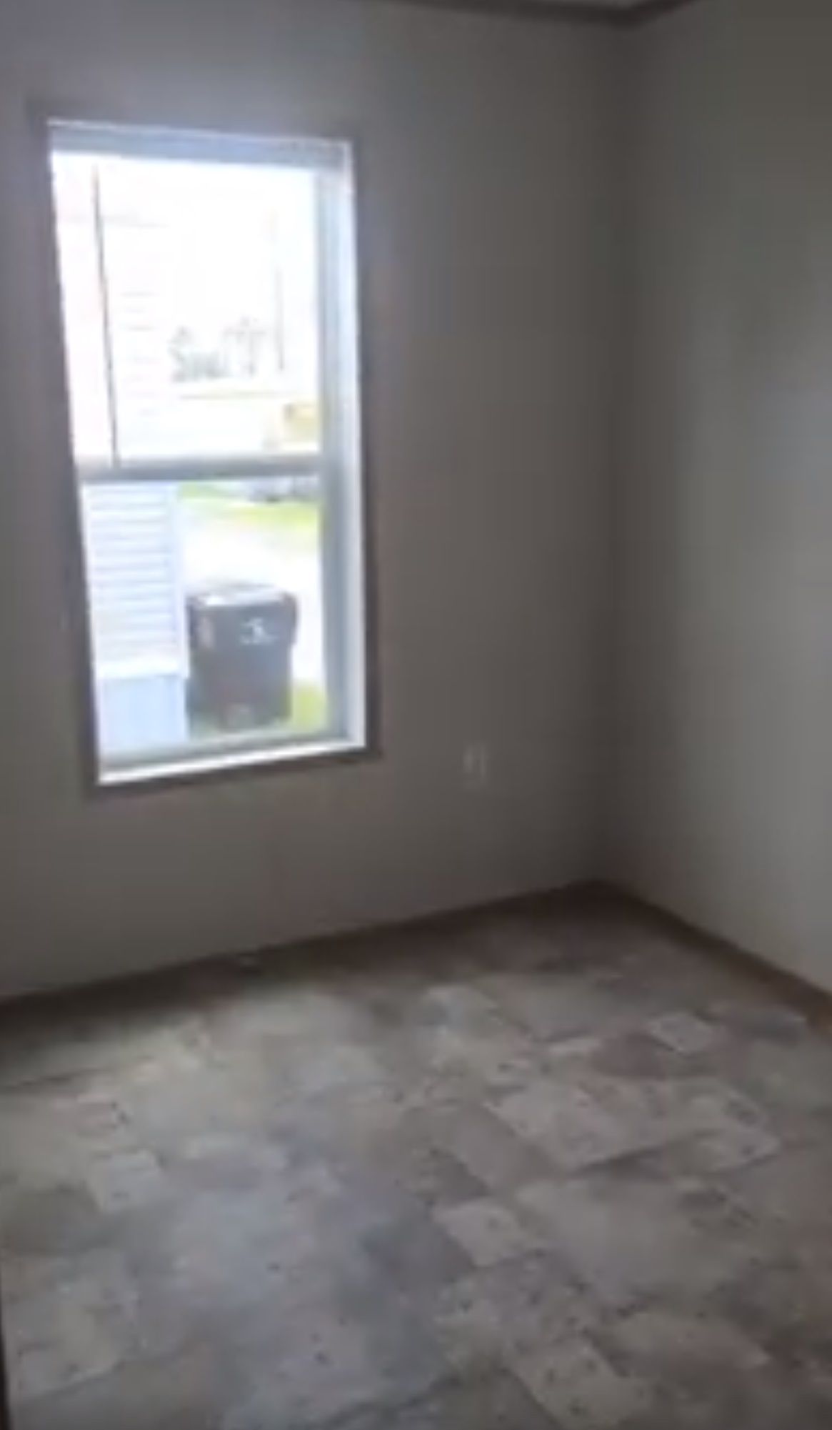 Empty room with a window, blinds, and patterned flooring.
