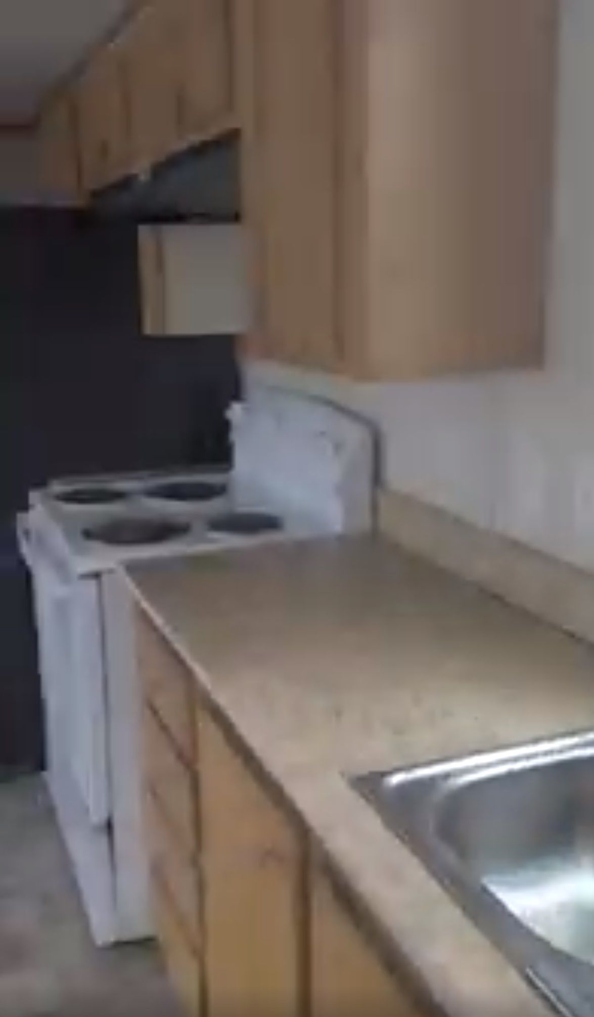 Kitchen with light cabinets, beige countertops, white appliances, and a stainless steel sink.
