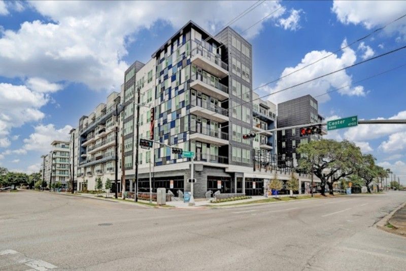 A large apartment building is sitting on the corner of a city street.