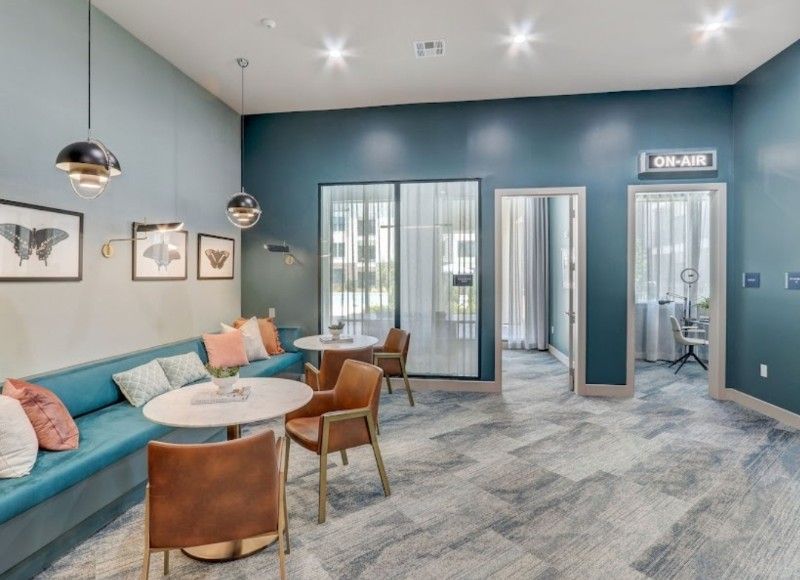 A living room with tables and chairs and a blue couch.