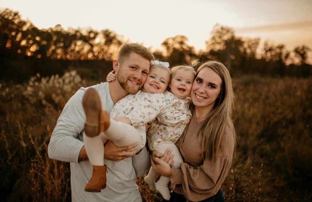 A family is posing for a picture in a field at sunset.