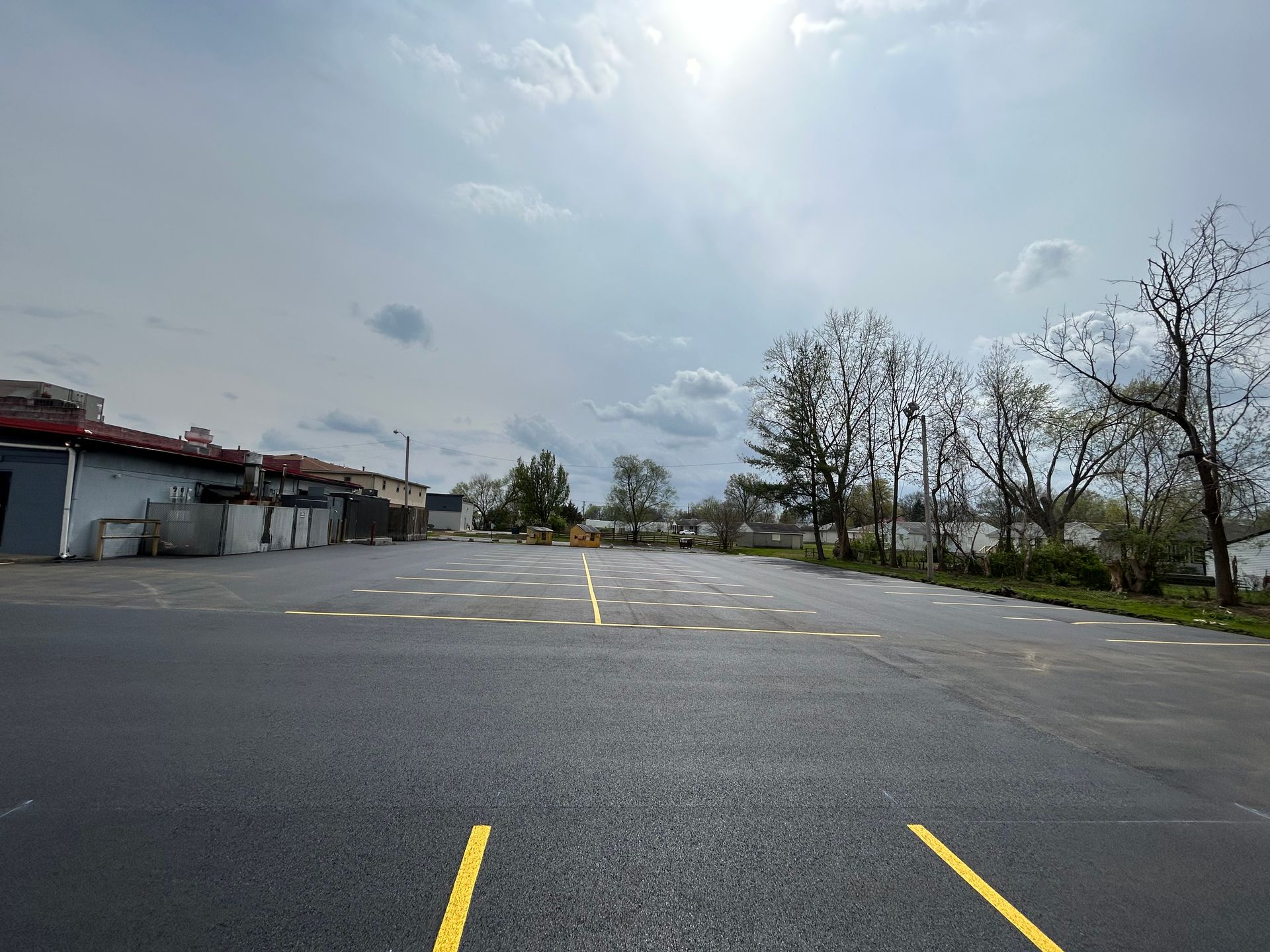 A parking lot with yellow lines and a building in the background.