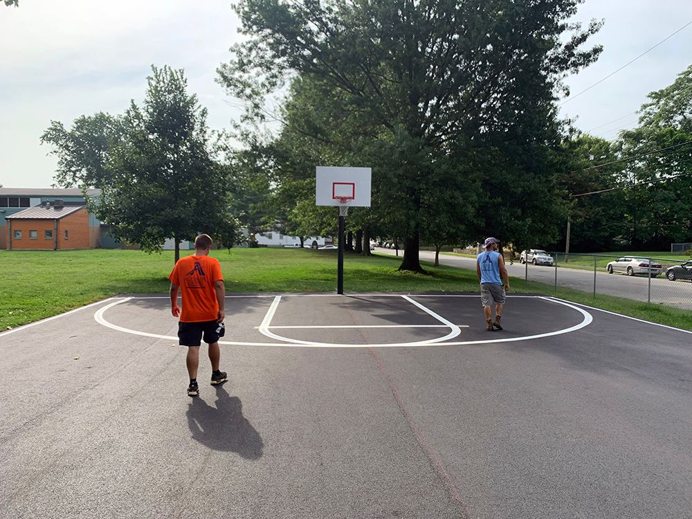 A man in an orange shirt is standing on a basketball court