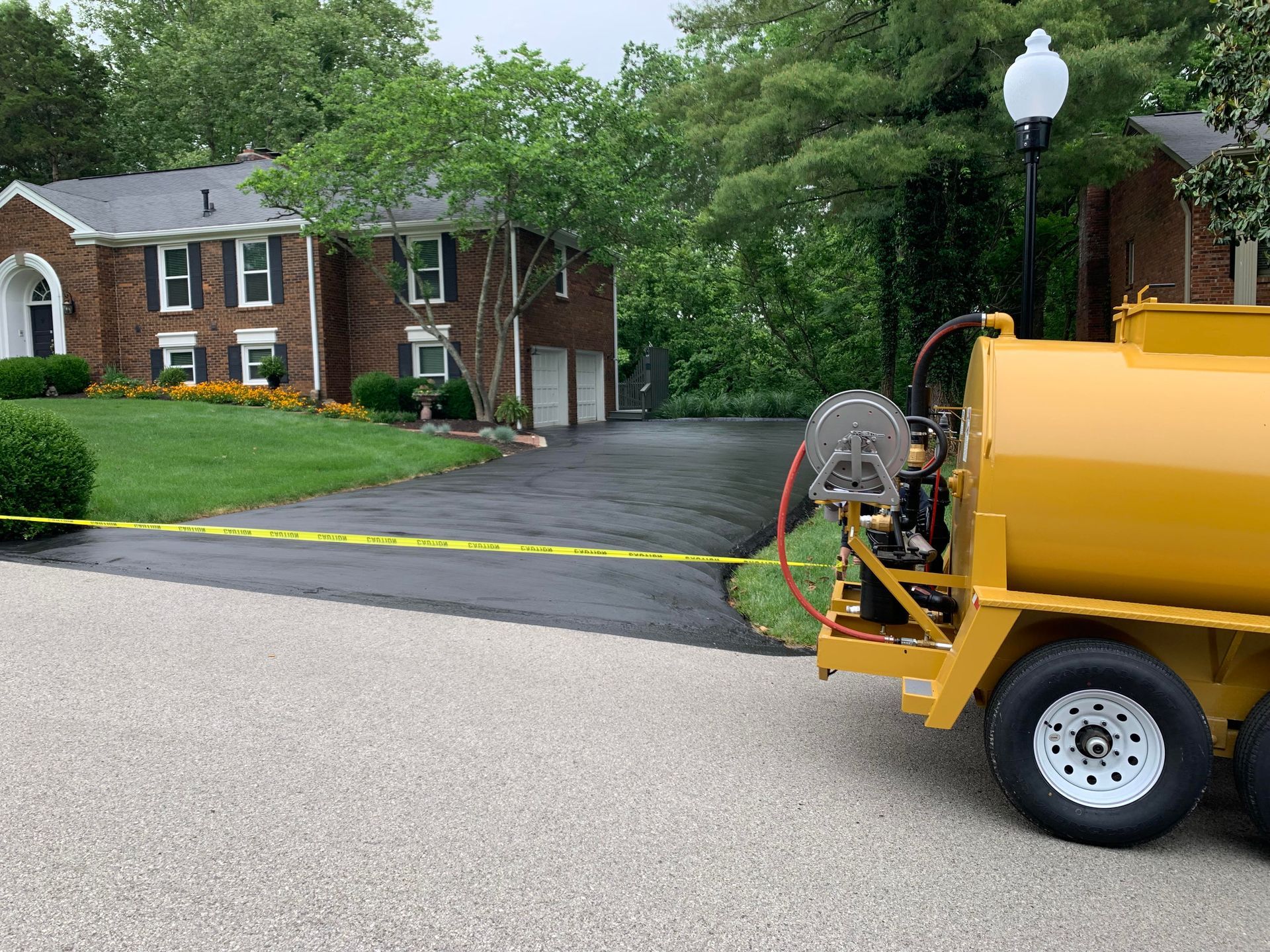 A yellow truck is parked in front of a brick house.
