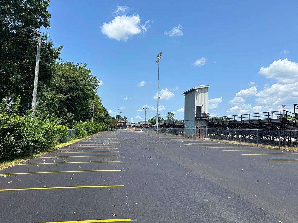 An empty parking lot with a stadium in the background on a sunny day.