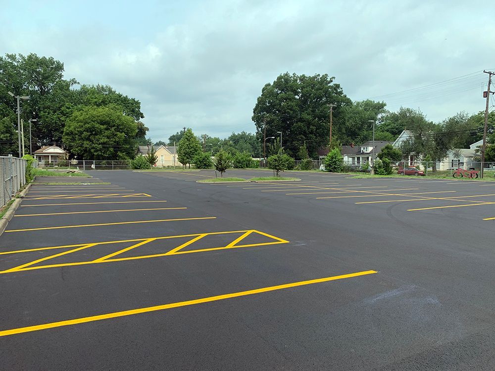 An empty parking lot with yellow lines and trees in the background