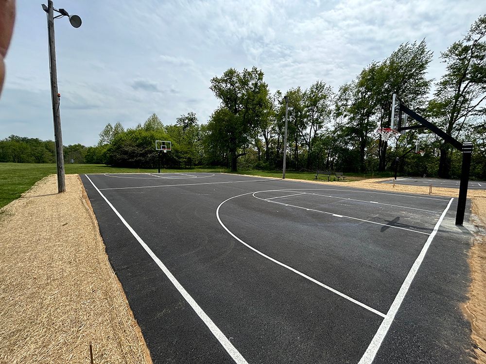A basketball court in a park with trees in the background