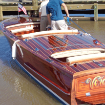 A man is standing on a wooden boat in the water.