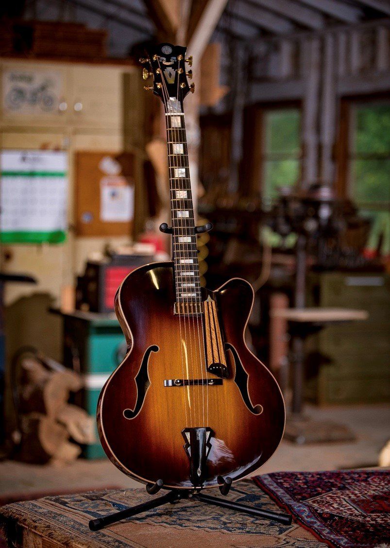 A guitar is sitting on a stand in a room.