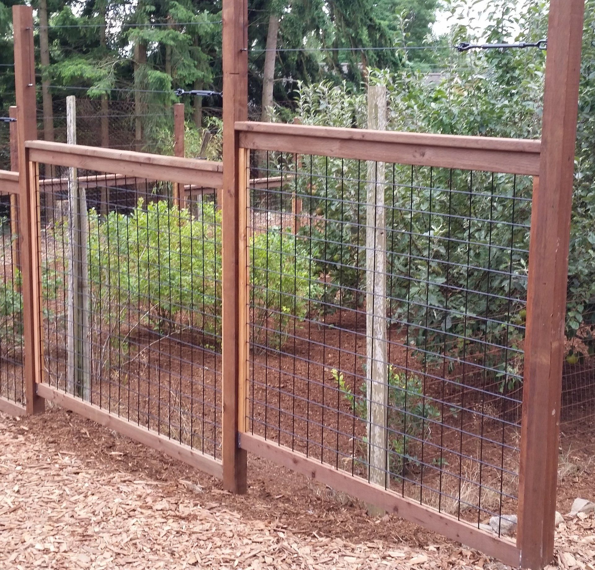 Brown wooden fence with black vertical rods, built in a yard.
